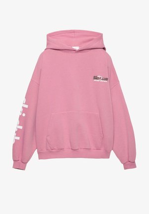 Ružová mikina s kapucňou, s predným vreckom, oversized strihom a textom "Ski Club Winter Series" v tmavosivej farbe na hrudi.