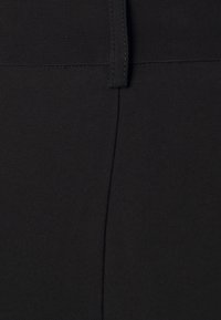 Tissu noir présentant une surface lisse et légèrement texturée. Le design comprend une ceinture et des détails de couture verticaux.