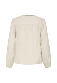 Blouse crème à manches longues vue de dos, avec empiècement froncé et manches à poignets, sans fermetures ni motifs visibles.