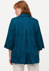 Teal jas met een gestructureerd bloemenpatroon, een kraag, driekwart mouwen met insnijdingen en een plooi aan de achterkant, gemaakt van een lichtgewicht stof.