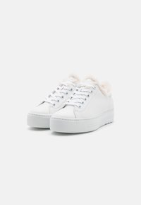 Weiße Sneaker mit einem glatten Leder-Obermaterial, kuscheligem Fellfutter am Kragen, flacher Gummisohle und sechs Metallösen für die Schnürsenkel.