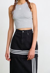 Grå randig crop top med rund hals och liten logotyp; kombinerad med svart jeanskjol med vita randiga detaljer och knappstängning.