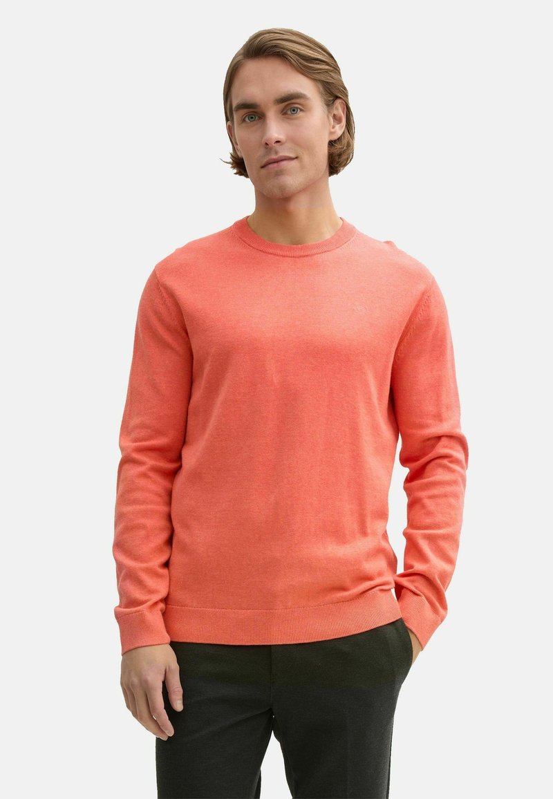 Pulover coral cu guler rotund, confecționat dintr-un material ușor. Prezintă mâneci lungi și mansete din tricot, asortat cu pantaloni închis la culoare. Textură netedă.
