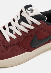 Tenisky Nike SB Force 58 majú vínovo červený zamakovaný zvršok, čierny kožený swoosh, smotánové šnúrky a béžovú gumenú podrážku so škvrnami.