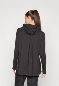 Svart långärmad hoodie med en avslappnad passform, featuring en huva, veckdetalj på baksidan och ett mjukt, stretchigt tyg.