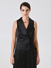 Blazer senza maniche in raso nero con colletto a scialle, bottoni doppi, abbinato a un bracciale in oro. Texture liscia.
