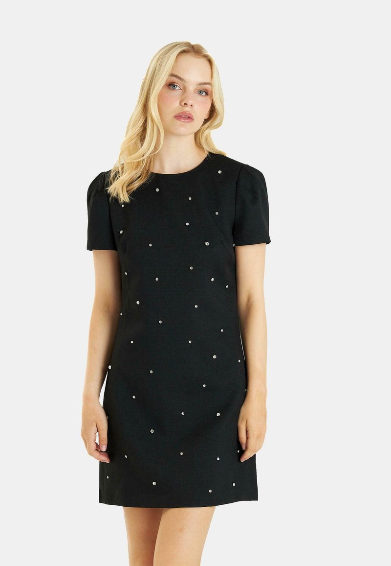 Vestido negro de manga corta con escote redondo y adornos plateados dispersos. La tela tiene una textura suave y un diseño ajustado.