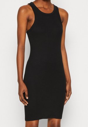 Woman wearing a sleeveless, fitted black dress with a round neckline, shown from shoulders to mid-thigh against a plain background.