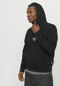 Schwarzer Hoodie aus Baumwollmischung, mit einer vorderen Kängurutasche, verstellbarem Kordelzugkapuze und gesticktem Logo auf der Brust.