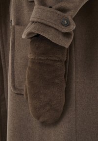 Brūns vilnas mēteļa piedurkne ar vilnas oderi brūnā cimdā. Mēteļa piedurkne ir ar pogu aproci un kabatu detaļām. Kopumā mīksta tekstūra.