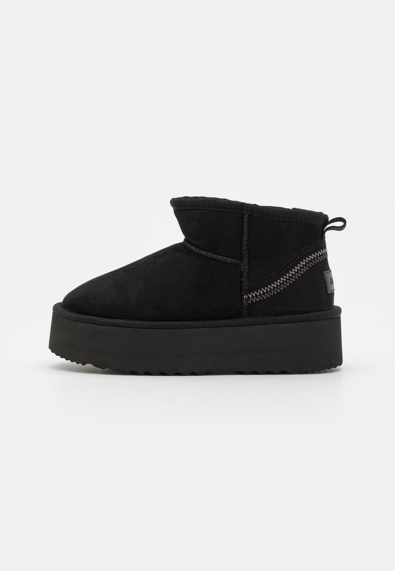 Botas de tobillo de ante negro con punta redonda, costura elástica a los lados y una suela gruesa negra. Presenta costuras visibles y una lengüeta en la parte posterior.