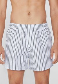 Boxers pour hommes en coton avec des rayures verticales bleues et noires, taille élastique et deux boutons à l'avant pour le maintien.