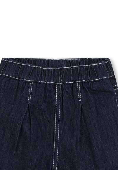 Pantaloni in denim di colore blu scuro, con cintura elasticizzata e cuciture bianche. La parte anteriore pettorata aggiunge struttura al design.