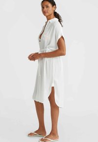 White, knee-length shirt dress with short sleeves, a collar, and a fabric belt. Soft texture with side slits and a relaxed fit.