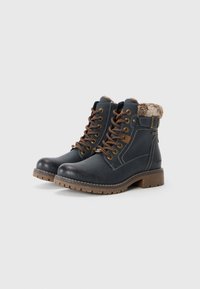Bottes d'hiver lacées bleu marine avec semelles marron, doublure en fausse fourrure à la cheville, œillets en métal et sangle à boucle sur le côté.