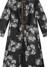 Kimono nero a fiori con motivo textured, caratterizzato da fiori bianchi prominenti e accenti marroni lungo l'apertura frontale. Maniche lunghe e design fluido.