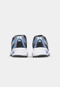 Chaussures de course en mesh noir avec des accents bleus. Semelle blanche rembourrée avec une adhérence texturée et des détails réfléchissants à l'arrière.