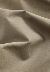 Beige textiel met een subtiele structuur en rimpels, gemaakt van een geweven materiaal. Het oppervlak lijkt glad met een lichte glans.