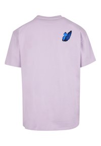 Lavendel bomull t-skjorte med korte ermer, med et blått sommerfuglgrafikk på baksiden. Enkelt design med klassisk rund hals.