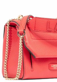 Sac à main en cuir texturé rouge avec une bandoulière en chaîne dorée, doté d'une fermeture à rabat et d'un lettrage en relief sur le devant.