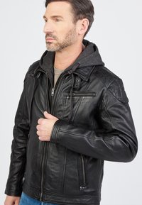 Zwarte leren jas met een grijze capuchon, ritszakken, gedetailleerde stiksels en een aansluitend ontwerp. Glad textuur met een moderne uitstraling.