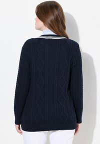 Navy Kabeltropfenpullover mit geripptem Saum und strukturierten Rautenmuster. Hat ein Detail am Hals mit weißen Streifen, lange Ärmel und eine lässige Passform.