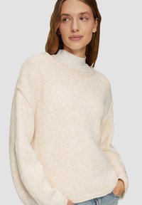 Cremfarbener Strickpullover mit lockerer Passform, Rundhalsausschnitt, gerippten Bündchen und einer weichen Textur. Trägt man über einem leichten Rollkragenpullover.