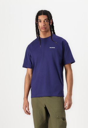 T-shirt court violet en coton avec un col rond, comportant un petit logo blanc "SALOMON" sur la poitrine.