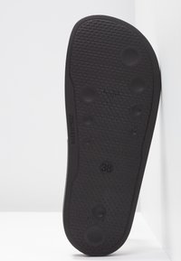 Semelle de chaussure en caoutchouc noir avec des motifs circulaires antidérapants et une indication de taille "38", photographiée sur fond blanc.
