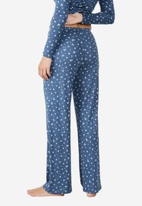 Conjunto de pijama azul con mangas largas y pantalones holgados, que presenta un patrón floral blanco y una tela suave y texturizada.