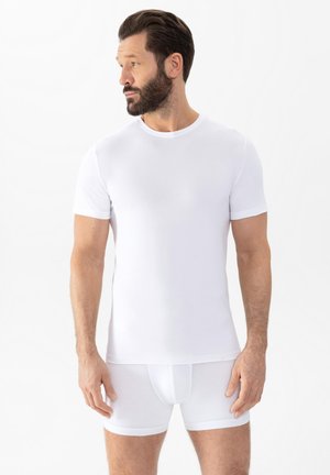 T-shirt blanche ajustée à manches courtes en coton doux et extensible. Encolure ronde et texture lisse, associée à un short blanc ajusté.