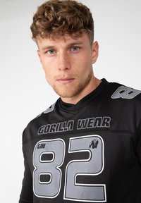 Zwarte sportshirt met "GORILLA WEAR" in vette letters, met grijze accenten, een groot "82" op de voorkant en een netstructuur voor ademend vermogen.