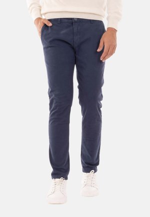 Chino blu navy realizzati in cotone morbido, con un design slim fit, tasche anteriori e chiusura con bottone in vita. Indossati con sneakers bianche.