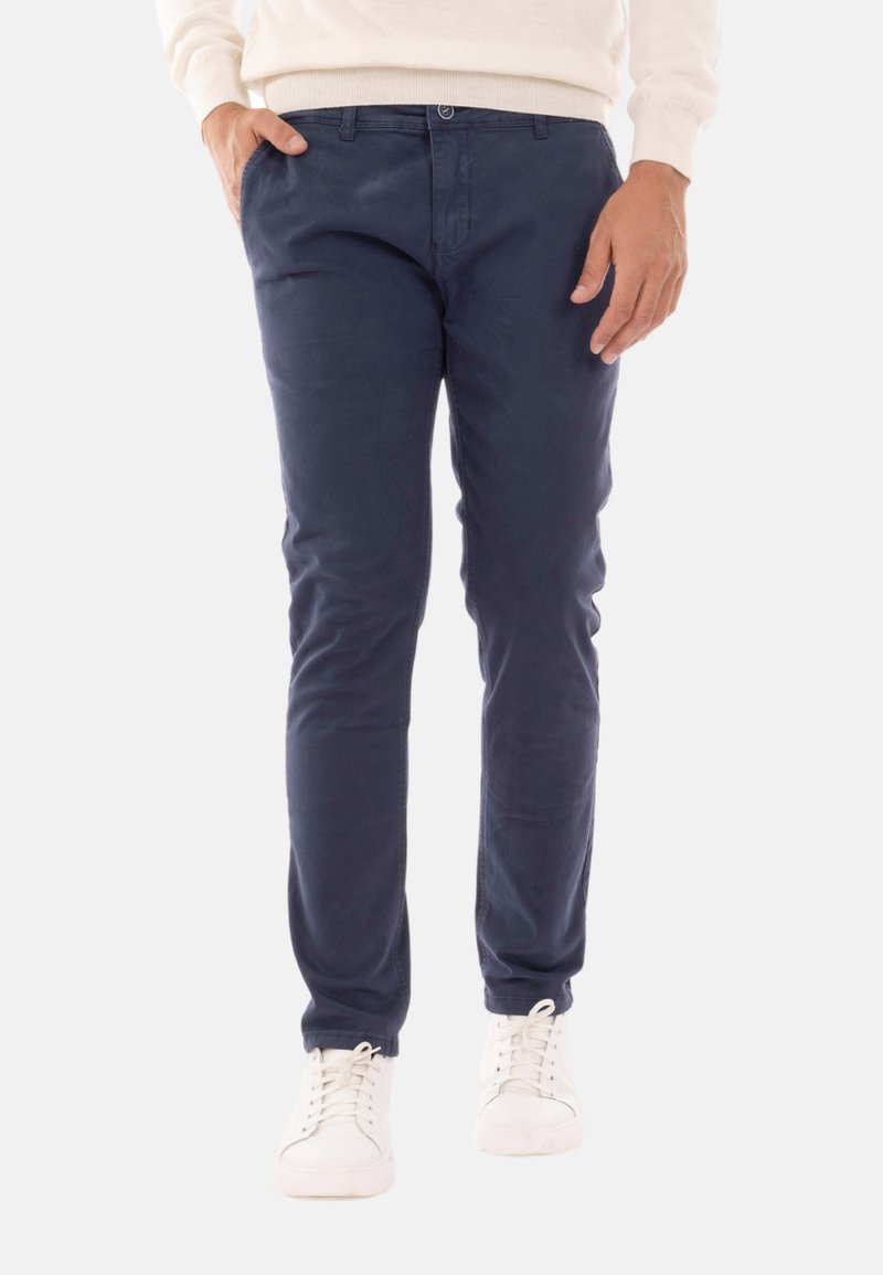 Chino blu navy realizzati in cotone morbido, con un design slim fit, tasche anteriori e chiusura con bottone in vita. Indossati con sneakers bianche.