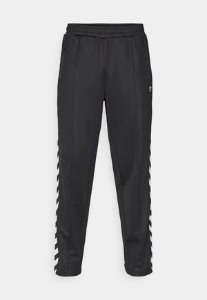 Zwarte sportbroek met een elastische tailleband, voorzien van zijzakken met rits en witte zigzagaccenten langs de zijkanten. Soepele textuur.