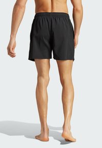 Black swim shorts made of lightweight fabric with an elastic waistband, side pockets, and a simple, smooth texture.