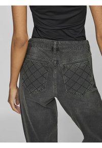 Los jeans de mezclilla gris oscuro cuentan con distintivos bolsillos traseros acolchados, una cintura alta y un ajuste relajado con detalles de costura visibles.