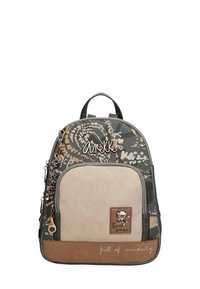 Mochila pequeña con bolsillo frontal beige, diseño en gris y marrón, emblema metálico de gato, cremallera y texto "llena de curiosidad" en el borde inferior.