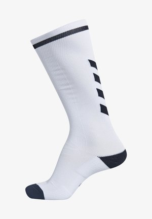 Calcetín deportivo blanco con puño acanalado, talón y puntera en azul marino oscuro, y rayas en contraste azul marino. Presenta tres acentos geométricos en azul marino en el lateral.