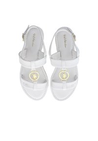 Bílé kožené sandály s nastavitelným zapínáním kolem kotníku, plochou podrážkou a kulatým zlatým akcentem na popruhu. Hladký povrch, jednoduchý design.