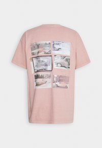 Lyserød bomulds-T-shirt med en collage af vintagebilfotos trykt på ryggen, med en afslappet pasform og rund halsudskæring.