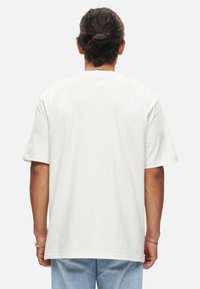 Witte katoenen t-shirt met een ontspannen pasvorm, korte mouwen en een ronde halslijn. Eenvoudig ontwerp zonder zichtbare patronen of logo's.