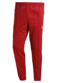 Červené sportovní kalhoty z měkké látky s úzkým střihem, elastickým pasem, bočními kapsami a bílým logem.