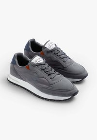 Graue Sneaker aus einer Kombination von Mesh- und Wildledermaterialien, mit einer weißen Zwischensohle und einer schwarzen Gummisohle. Auffälliger orangefarbener Akzent.