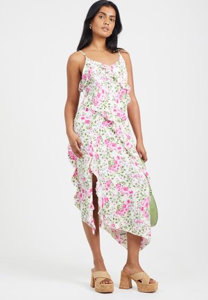 Bloemige maxi jurk met roze en groene patronen, ruches aan de rand, zijsplitten en verstelbare spaghettibandjes. G gedragen met tan platform sandaaltjes.
