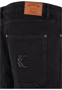 Jeans in denim nero con etichetta in pelle, dotati di due tasche posteriori, una con dettaglio del logo ricamato in nero e rivetti metallici.