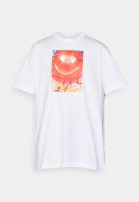 Witte t-shirt met korte mouwen, voorzien van een kleurrijke glimlachende basketbalafbeelding met neonlichteffecten in rode, oranje, roze en blauwe tinten.