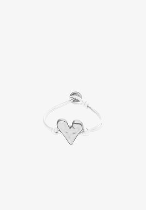 Bracelet en corde blanche réglable avec un pendentif en forme de cœur en argent poli au centre et une fermeture par boucle.