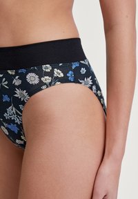 Sous-vêtements hipster noirs à motif floral avec une ceinture élastique noire ; ornés de fleurs bleues et blanches et d'un tissu lisse et extensible.