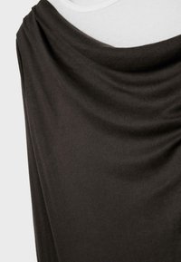 Tessuto nero drappeggiato con pieghe morbide su una forma bianca, che evidenzia una trama liscia e dettagli sottili a coste.